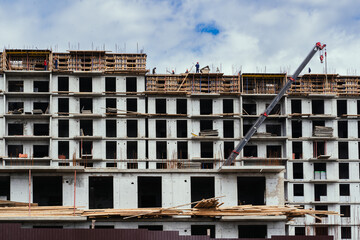 The ongoing construction of a multistory building features cranes and scaffolding raised overhead