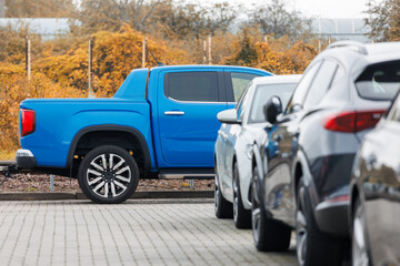 Side view of blue new ev pickup truck parked at outdoor parking lot automobile dealer or parking place against autumn foliage. Modern SUV electric vehicle outside © K-FK