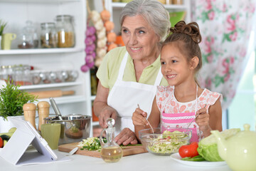 Grandmother with her granddaughter preparing a salad in the kitchen
