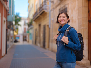 Young woman strolling through charming narrow streets of Denia, Alicante province, Spain, surrounded by historic Mediterranean architecture , enjoying peaceful atmosphere and cultural ambiance.