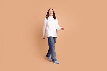 Fototapeta premium Photo of cheerful optimistic woman wear white stylish clothes go empty space isolated on beige color background