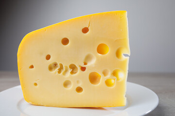 maasdam cheese on a plate, grey background