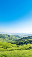 Obraz premium Vast landscape of rolling green hills under clear blue sky, evoking tranquility.