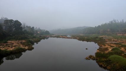 Serene river landscape with lush greenery and misty atmosphere.