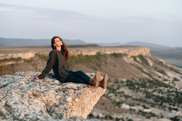 Majestic view of woman sitting on cliff gazing at utah mountains and valley landscape