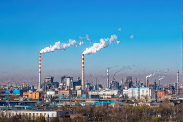 Industrial factories emitting smoke from chimneys, symbolizing air pollution and environmental impact against a clear blue sky. Generative AI