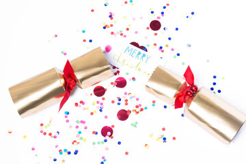 Isolated Christmas golden color pulled cracker, card with text “Merry Christmas” and confetti, holiday festive cracker on white background, holiday concept