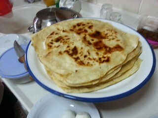 A plate of freshly made flatbreads, their golden-brown spots reflecting the warmth and tradition of homemade food, symbolizing the comfort and simplicity of traditional cuisine shared among family.