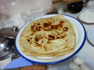 A plate of freshly made flatbreads, their golden-brown spots reflecting the warmth and tradition of homemade food, symbolizing the comfort and simplicity of traditional cuisine shared among family.