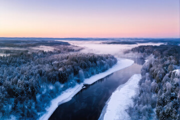 Obraz premium A panoramic winter landscape featuring a winding river through a snow-covered forest, with soft morning mist and pastel skies creating a serene scene. Generative AI