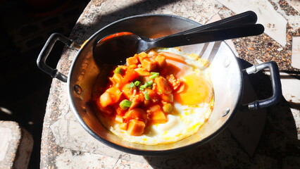 pan-fried egg with toppings, a breakfast of hot dog and fried egg in a small pan, shined by the warm morning sunlight