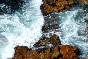 White and blue effects and trails generated by the undertow of the waves on the rocks