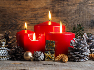 Red Advent candles on a rustic wooden background, fourth candle is burning