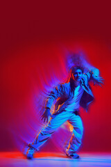 Creative design. Energetic performance of young man in casual clothes dancing hip hop, freestyle dance on red background with light wave effect. Concept of dance, art, modern style, youth culture