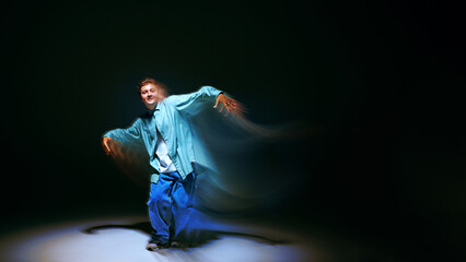 Creative design. Young man in casual clothes dancing contempt, freestyle, hip hop against black...