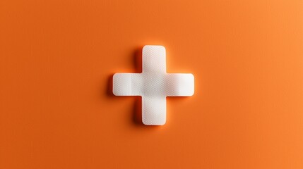 Obraz premium Adhesive plaster in a cross shape symbolizes medical aid on an orange background.