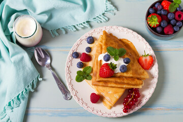 Crepes, thin pancakes  with yogurt and berries. Healthy food for breakfast. Top view