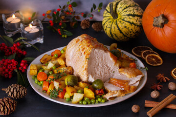 Roasted rolled and boned turkey breast fillet with potatoes, carrots, turnip and brussel sprouts. Thanksgiving autumn dinner table with decorations. View from above