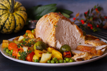 Roasted rolled and boned turkey breast fillet with potatoes, carrots, turnip and brussel sprouts. Thanksgiving autumn dinner table with decorations. View from above