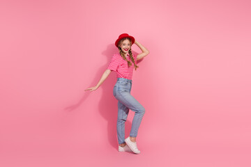 Stylish young woman in casual fashion posing joyfully on a bright pink background