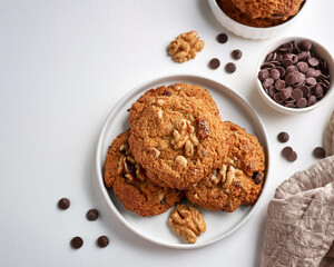 Freshly baked vegan oatmeal cookies with nuts and raisins, arranged in a pile against a white background, ai.