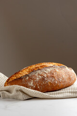 This image showcases a freshly baked, crispy golden bread loaf on a pristine marble kitchen surface, highlighting the texture and artisanal quality of the bread.