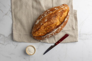 This image showcases a freshly baked, crispy golden bread loaf on a pristine marble kitchen...