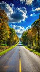 A scenic view of a long road surrounded by vibrant autumn trees under a clear blue sky.