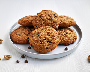 A stack of freshly baked vegan oatmeal cookies with nuts and raisins on a white background, ai.