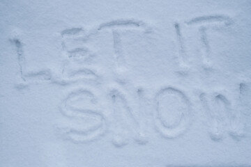 LET IT SNOW text handwritten in snowy winter season surface. Freezing cold weather. Climate change challenging conditions concept