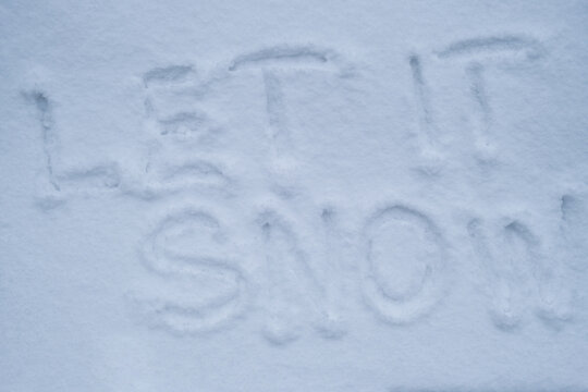 LET IT SNOW text handwritten in snowy winter season surface. Freezing cold weather. Climate change challenging conditions concept