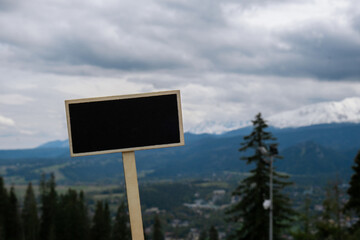 Empty blackboard label with copy space on background of Snowy mountains, green forests In National park Zakopane Poland. Mountain nature landscape. Travel outdoors green tourism concept Naturecore