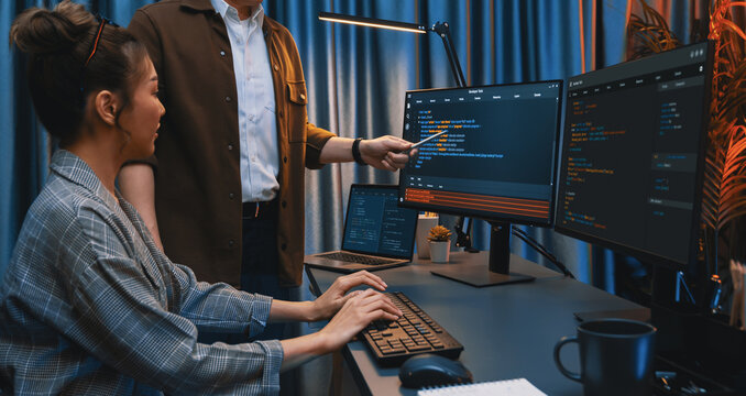 IT developers discussing with point to intelligent website development coder system running data online two screens information technology at neon light room at modern office. Infobahn.