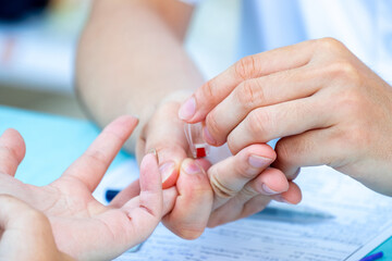 Doctor is drawing blood from fingertip to test patient's blood type, blood thickness measurement,...