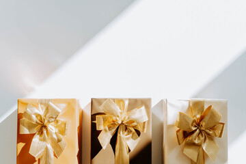 Three Christmas gift boxes, adorned with vibrant golden ribbons on white background with shadows