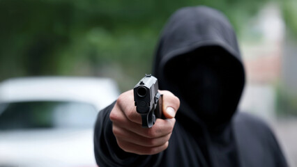 man in black hoodie is pointing handgun, creating tense atmosphere