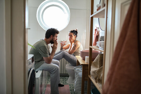 Smiling woman showing positive pregnancy test to boyfriend in bathroom