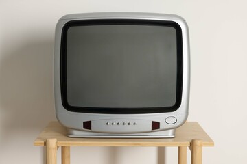 Retro tv set on wooden shelf against white wall