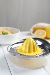 Plastic juicer and fresh lemons on white wooden table, closeup