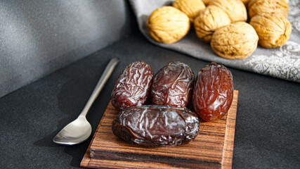 Dates and walnuts, fruit dessert, healthy snack from dried fruits, beautiful ripe date fruits on wooden square cup, on gray background, Italy
