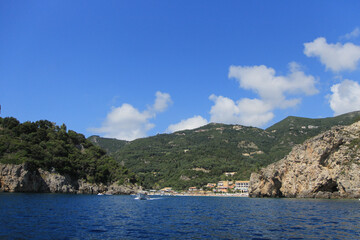 Fototapeta premium Scenic Greek Islands Landscape: Rock Formations, Cliffs, and Coastal Houses Viewed from the Sea