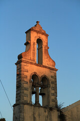 Concrete Bell Tower with Copper Green Bells: Street-Level View of a Sunlit Structure on a Greek Island