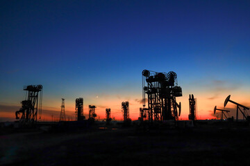 A silhouette of a pumping unit working in the evening