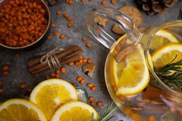 Buckthorn berries and orange tea in transparent teapot Cinnamon sticks tied with thread