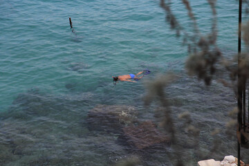 Man Snorkeling Face Down in the Sea: Surrounded by Crystal Clear Blue Waters and Greek Islands