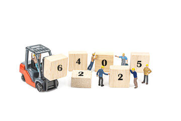 miniature worker team building standing front of forklift machine with 2025 number on wooden block...