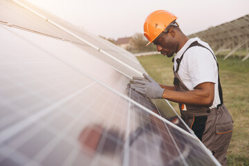 African American Male Engineer Inspecting Solar Panels at Renewable Energy Facility