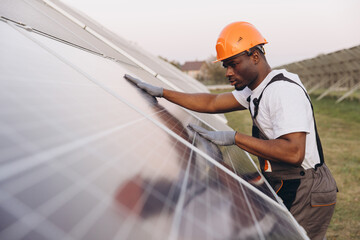 African American Male Engineer Inspecting Solar Panels at Energy Site Wearing Safety Gear