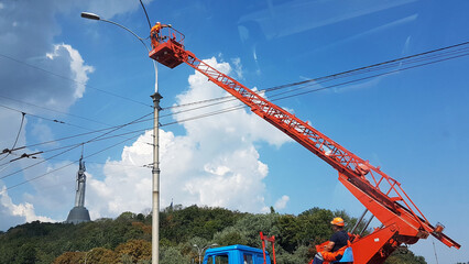 Electricians using an electrical installation tower repair street lighting in the city of Kyiv in Ukraine. Maintenance of city electrical networks. Modern professions of the city budget