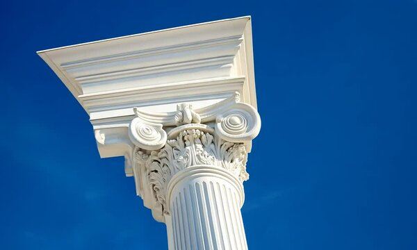 Ornate white column against a clear blue sky with clouds.